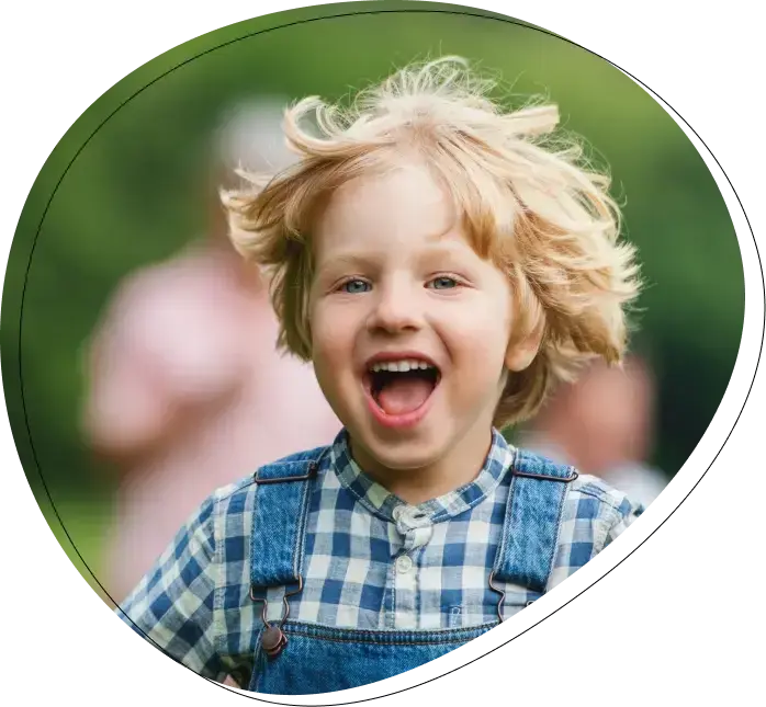 Happy young child with blonde hair smiling brightly during dental care visit.