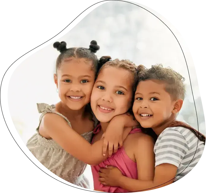 Three smiling children hugging together, representing happy dental patients in Oakmont, PA.
