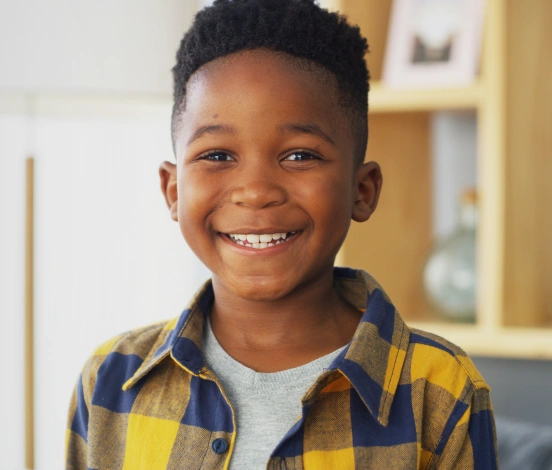 Smiling young Black boy wearing a yellow and blue plaid shirt